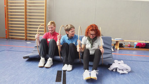 Die Referentin und zwei Teilnehmerinnen sitzen mit angewinkelten Beinen auf einer Matte.